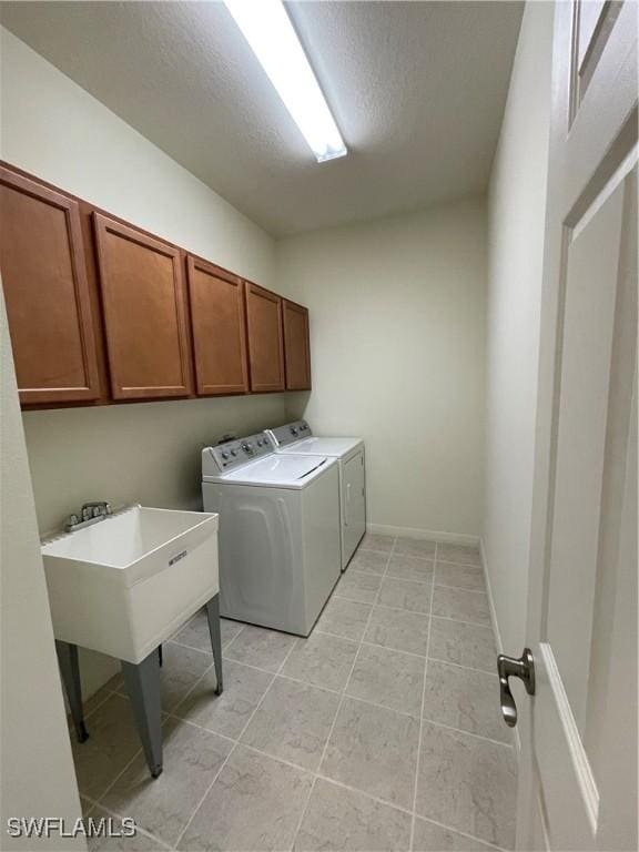 washroom featuring cabinets, a textured ceiling, and washer and clothes dryer