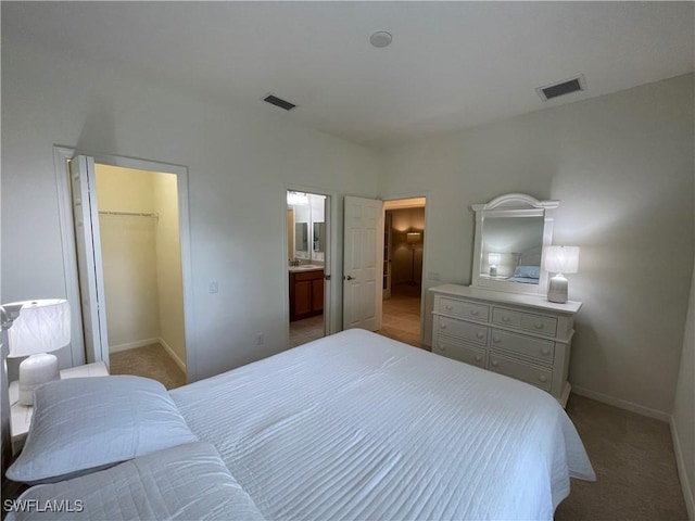 carpeted bedroom with a walk in closet, ensuite bathroom, and a closet