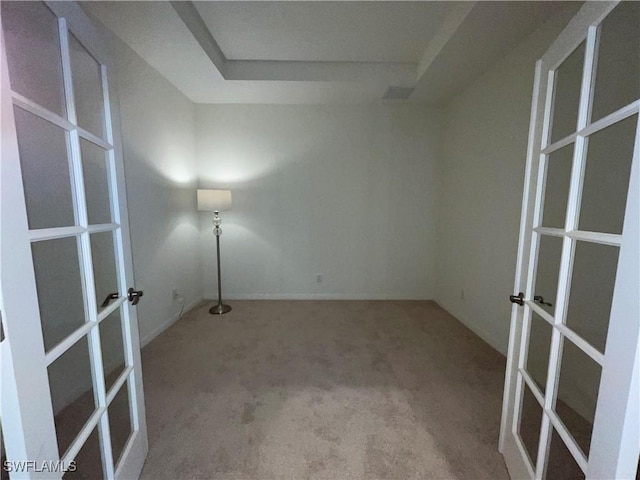 carpeted empty room featuring a tray ceiling