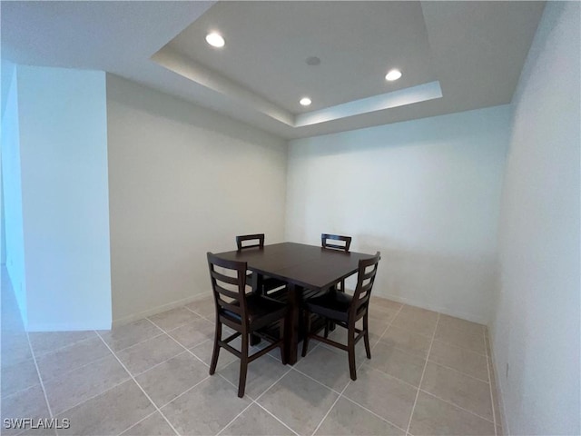 dining room with a tray ceiling and light tile patterned floors