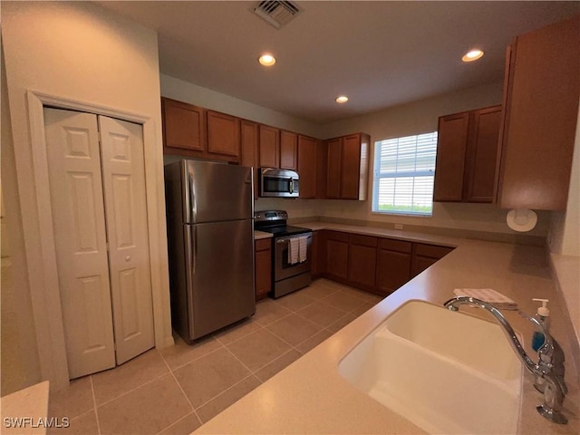 kitchen with light tile patterned flooring, stainless steel appliances, and sink