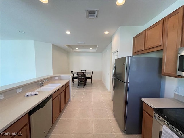 kitchen featuring light tile patterned flooring, a raised ceiling, sink, and appliances with stainless steel finishes