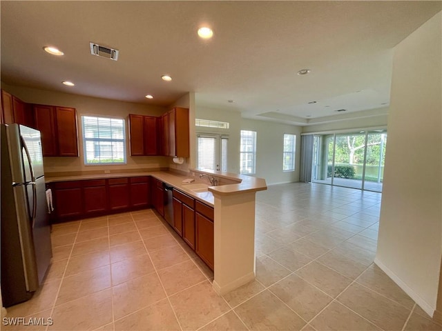 kitchen featuring kitchen peninsula, appliances with stainless steel finishes, light tile patterned floors, and sink