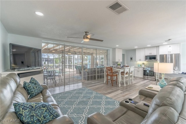 living room with ceiling fan and light hardwood / wood-style flooring