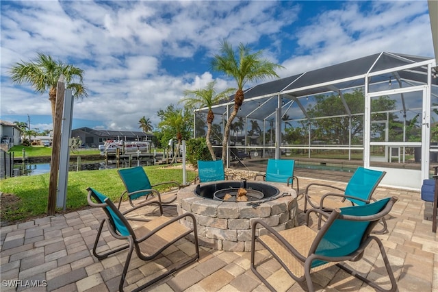 view of patio / terrace featuring a fire pit, glass enclosure, and a water view