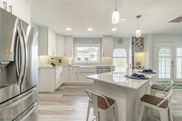 kitchen featuring a center island, a kitchen breakfast bar, decorative light fixtures, white cabinets, and appliances with stainless steel finishes