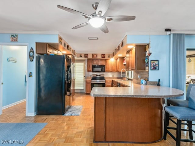 kitchen with black appliances, decorative backsplash, kitchen peninsula, and light parquet floors