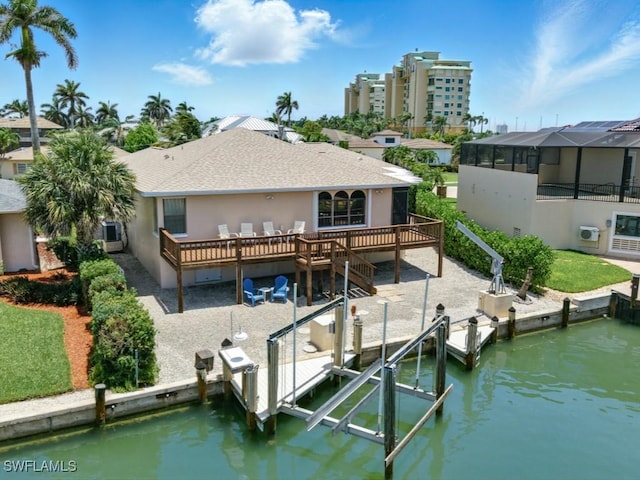 851 Perrine Ct, Marco Island, FL 34145 - rear view of house with boat lift, stucco siding, a deck with water view, and a shingled roof