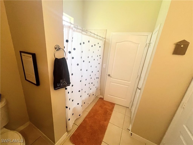 bathroom with tile patterned flooring, a shower with shower curtain, and toilet