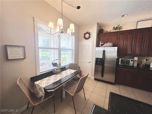 kitchen featuring decorative backsplash, stainless steel fridge, light tile patterned floors, decorative light fixtures, and a chandelier