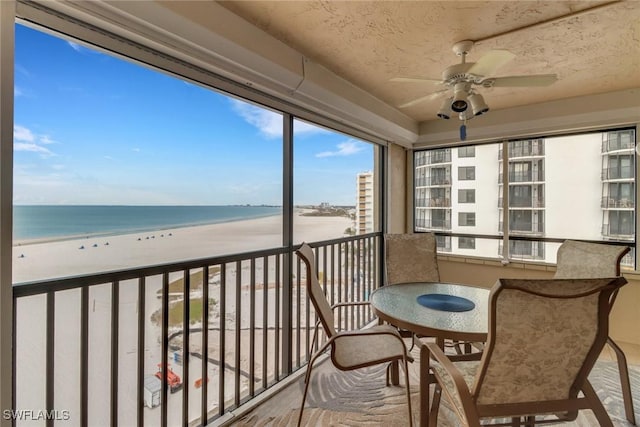 balcony featuring a water view, ceiling fan, and a view of the beach