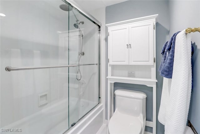 bathroom with toilet and bath / shower combo with glass door