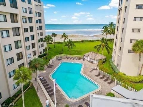 view of pool with a patio area, a water view, and a view of the beach