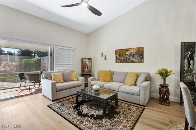 living room with ceiling fan, vaulted ceiling, and light wood-type flooring