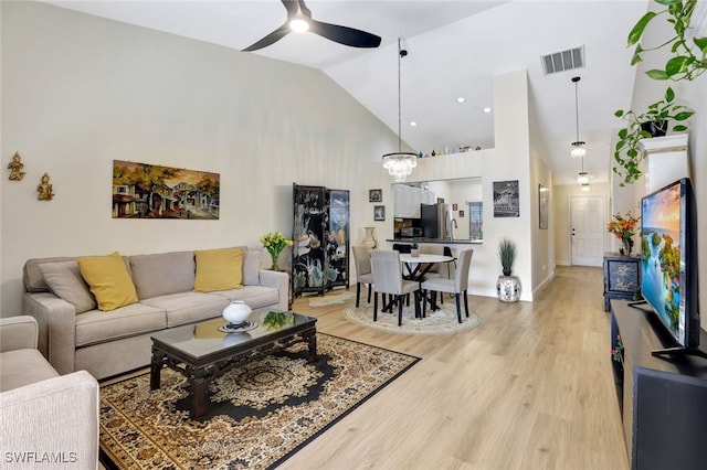 living room with hardwood / wood-style floors, ceiling fan with notable chandelier, and high vaulted ceiling