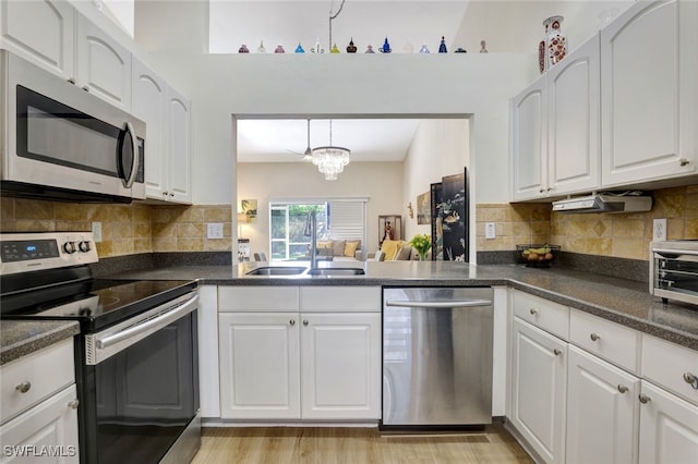 kitchen featuring white cabinets, sink, decorative light fixtures, a notable chandelier, and stainless steel appliances