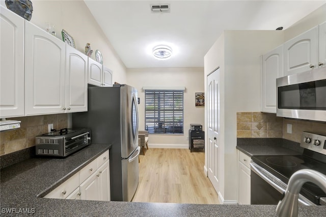 kitchen with appliances with stainless steel finishes, backsplash, and white cabinetry