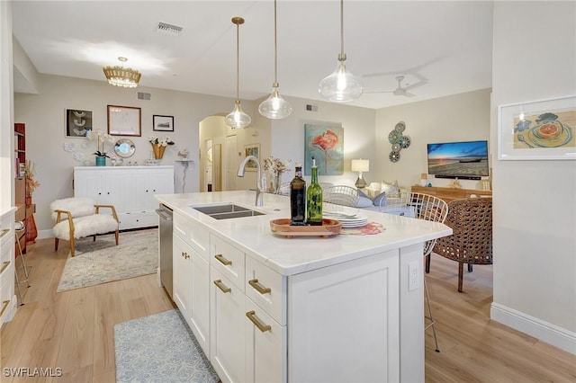 kitchen featuring sink, hanging light fixtures, a center island with sink, dishwasher, and white cabinets