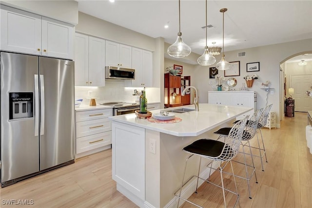 kitchen featuring sink, a breakfast bar area, white cabinetry, appliances with stainless steel finishes, and a kitchen island with sink