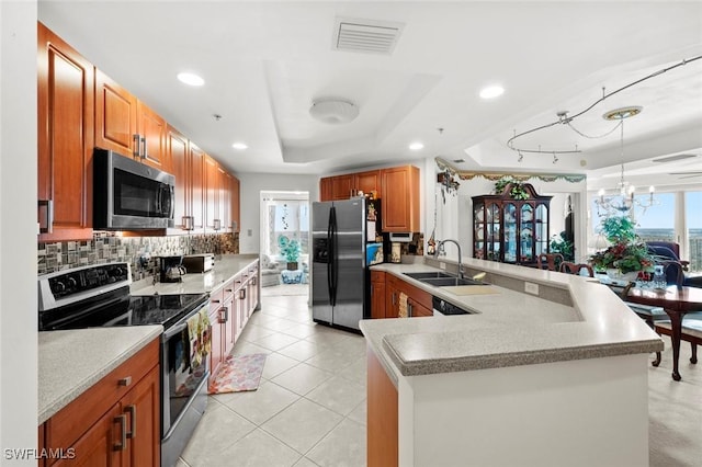 kitchen featuring backsplash, a raised ceiling, sink, kitchen peninsula, and stainless steel appliances