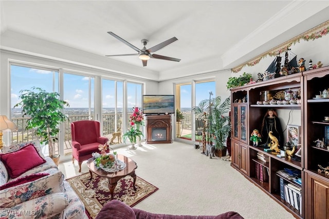 carpeted living room with ceiling fan and crown molding