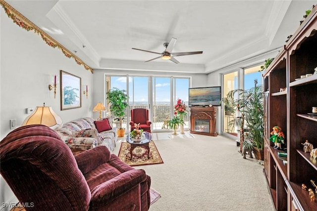 living room featuring a tray ceiling, a wealth of natural light, carpet flooring, and ceiling fan