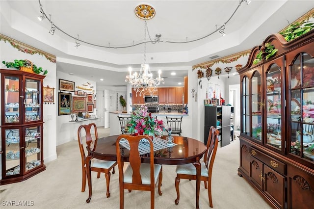 carpeted dining room with a raised ceiling and a chandelier