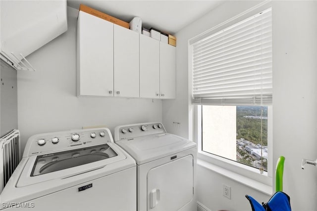 clothes washing area featuring cabinets, radiator, and washing machine and clothes dryer