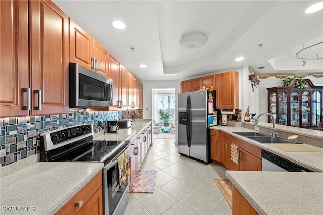 kitchen featuring backsplash, stainless steel appliances, a raised ceiling, sink, and light tile patterned floors