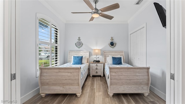 bedroom featuring hardwood / wood-style floors, ceiling fan, ornamental molding, and a closet