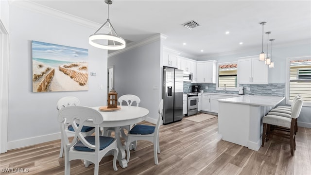 kitchen with a wealth of natural light, white cabinetry, decorative light fixtures, and appliances with stainless steel finishes