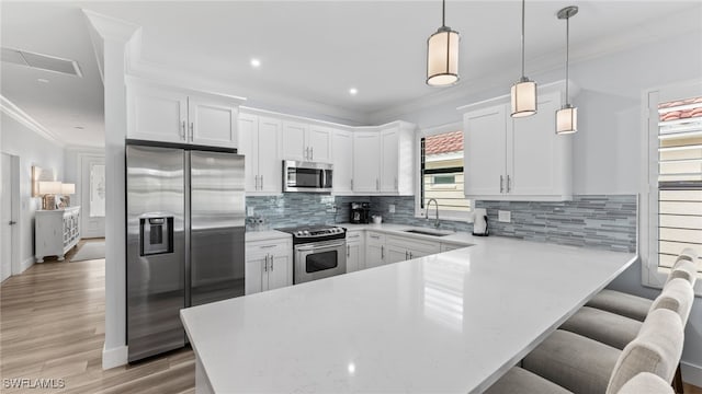 kitchen featuring appliances with stainless steel finishes, white cabinetry, hanging light fixtures, and plenty of natural light