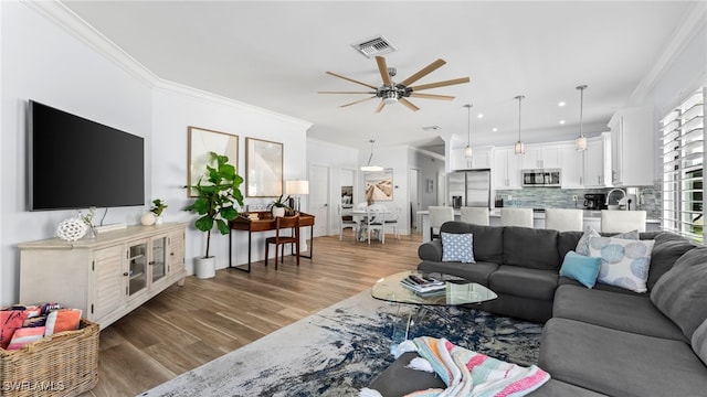 living room featuring hardwood / wood-style flooring, ceiling fan, and ornamental molding