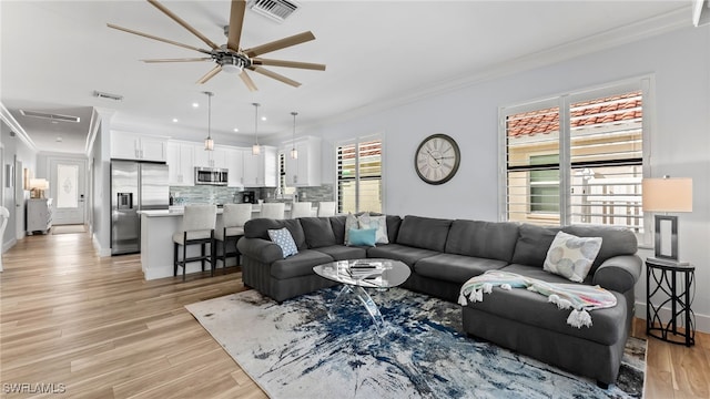 living room with ceiling fan, light wood-type flooring, and crown molding