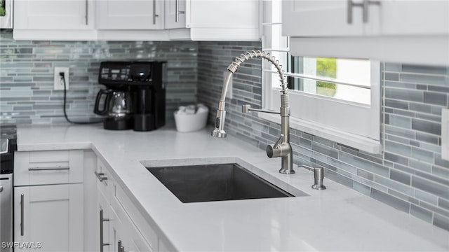 kitchen with white cabinets, decorative backsplash, and sink