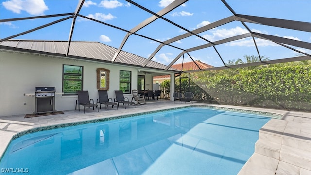 view of pool with glass enclosure, ceiling fan, a patio, and grilling area