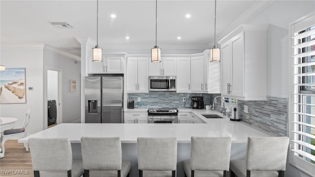 kitchen featuring white cabinets, a kitchen breakfast bar, stainless steel appliances, and hanging light fixtures