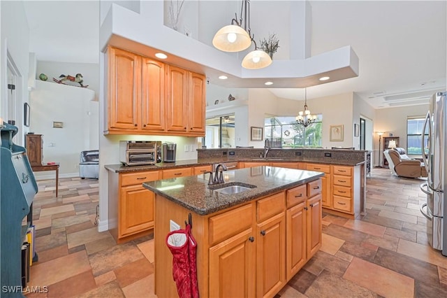 kitchen featuring a center island with sink, a high ceiling, hanging light fixtures, kitchen peninsula, and sink