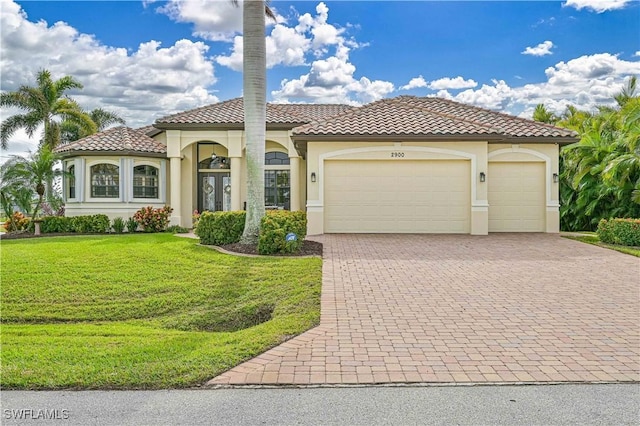 mediterranean / spanish-style home featuring a garage and a front lawn