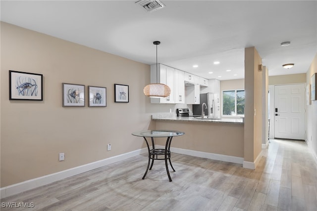 kitchen with light stone counters, kitchen peninsula, light hardwood / wood-style floors, decorative light fixtures, and white cabinets