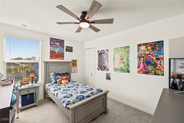 bedroom with ceiling fan, light carpet, and a closet