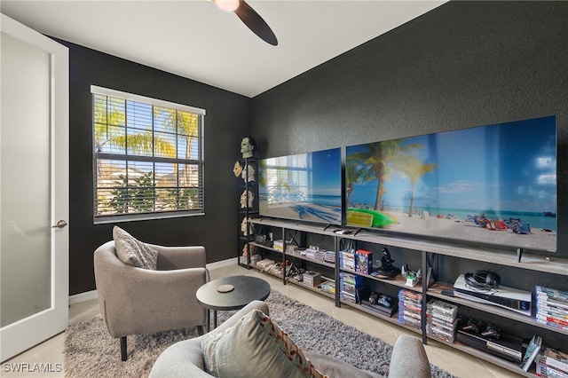 living area with ceiling fan and tile patterned flooring