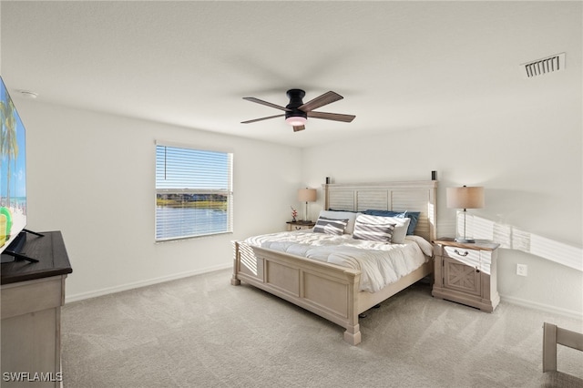 carpeted bedroom featuring ceiling fan and a water view