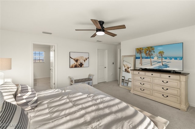 bedroom with ceiling fan, light colored carpet, and ensuite bathroom