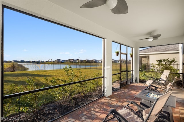 sunroom with a water view and ceiling fan