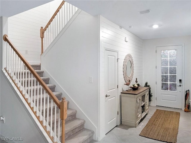 tiled foyer entrance with wood walls