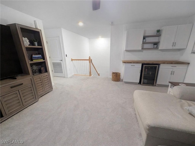 interior space featuring wine cooler, white cabinetry, light colored carpet, and wooden counters