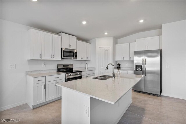 kitchen featuring sink, light stone counters, a center island with sink, white cabinets, and appliances with stainless steel finishes