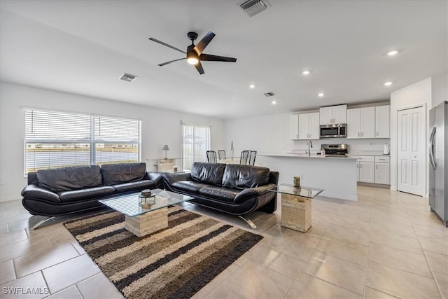 living room featuring ceiling fan, sink, and light tile patterned flooring