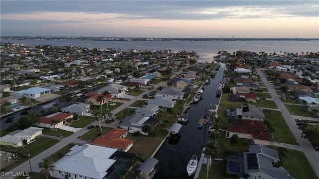 aerial view at dusk featuring a water view